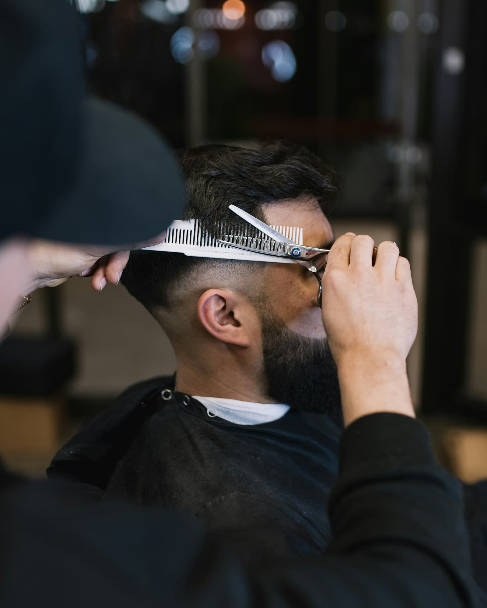 Barber mid-cut, scissors in hand, working on a client in a real shop